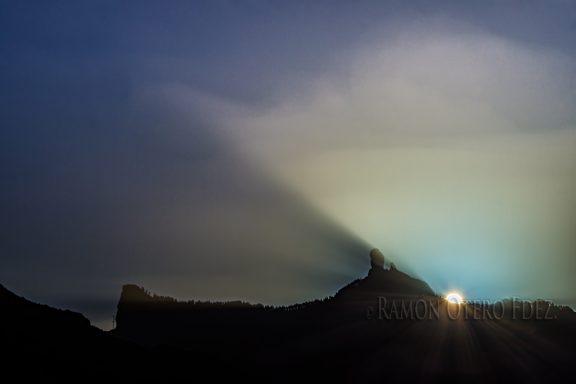 Rayo de luz del sol detrás de montañas, creando un efecto atmosférico.